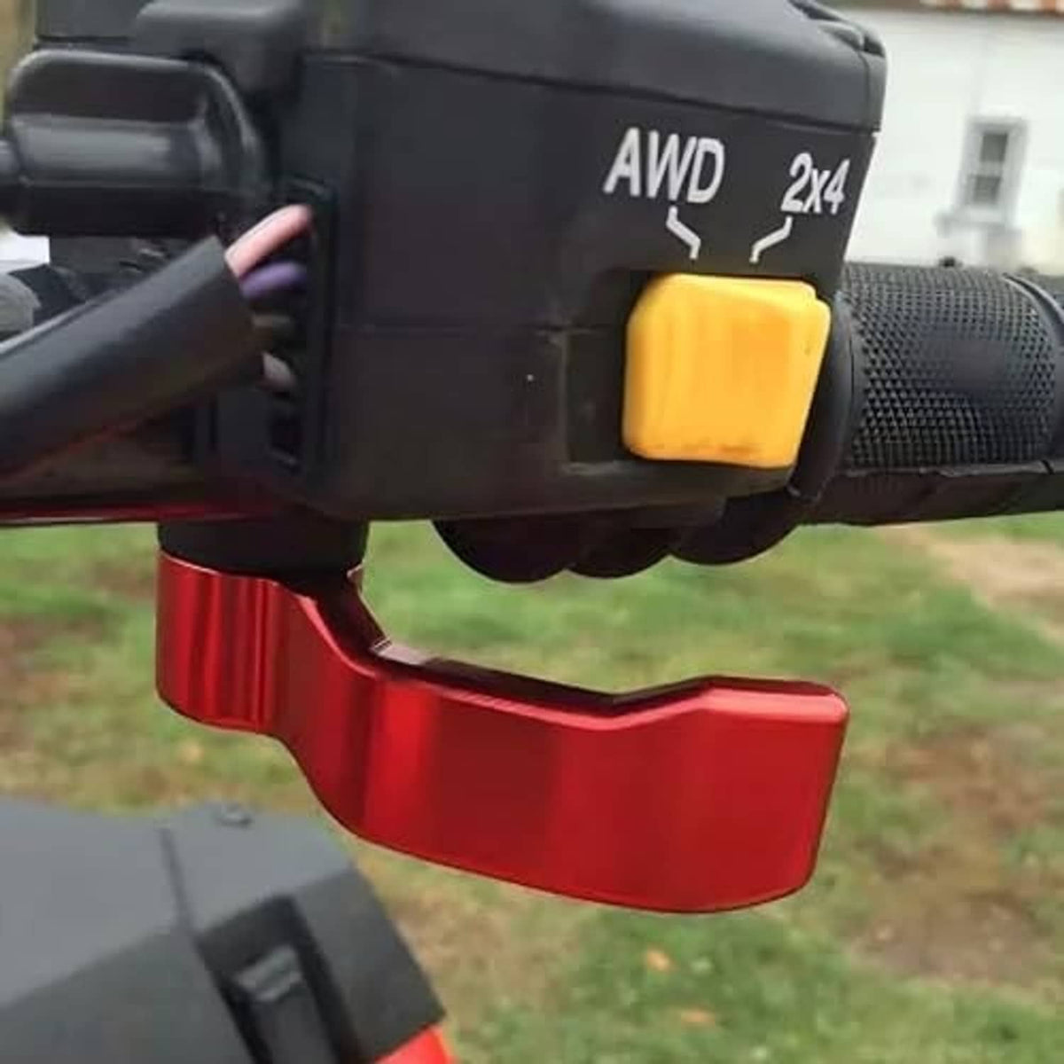 Red thumb throttle lever attached to black ATV handlebar housing