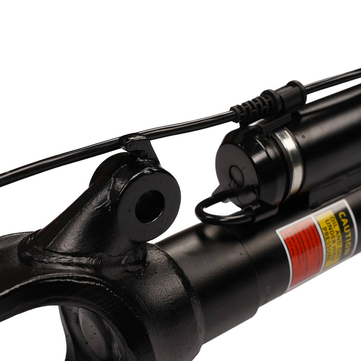 Close-up of black front air strut with mounting eye and warning label