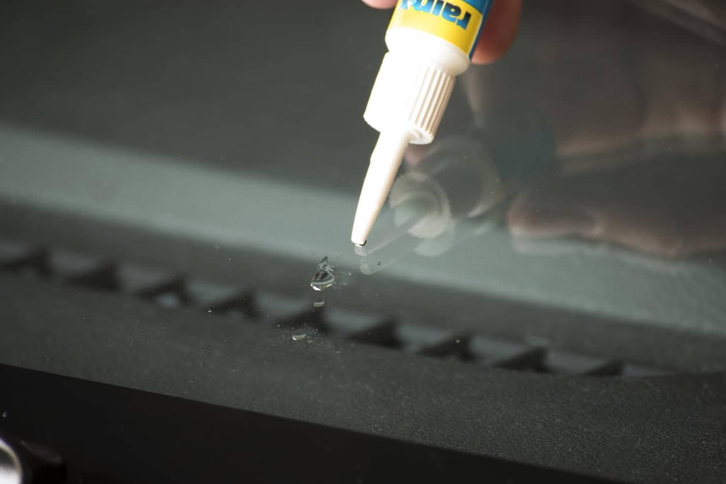 Rain-x windshield repair resin tip applying sealant to a small crack in glass