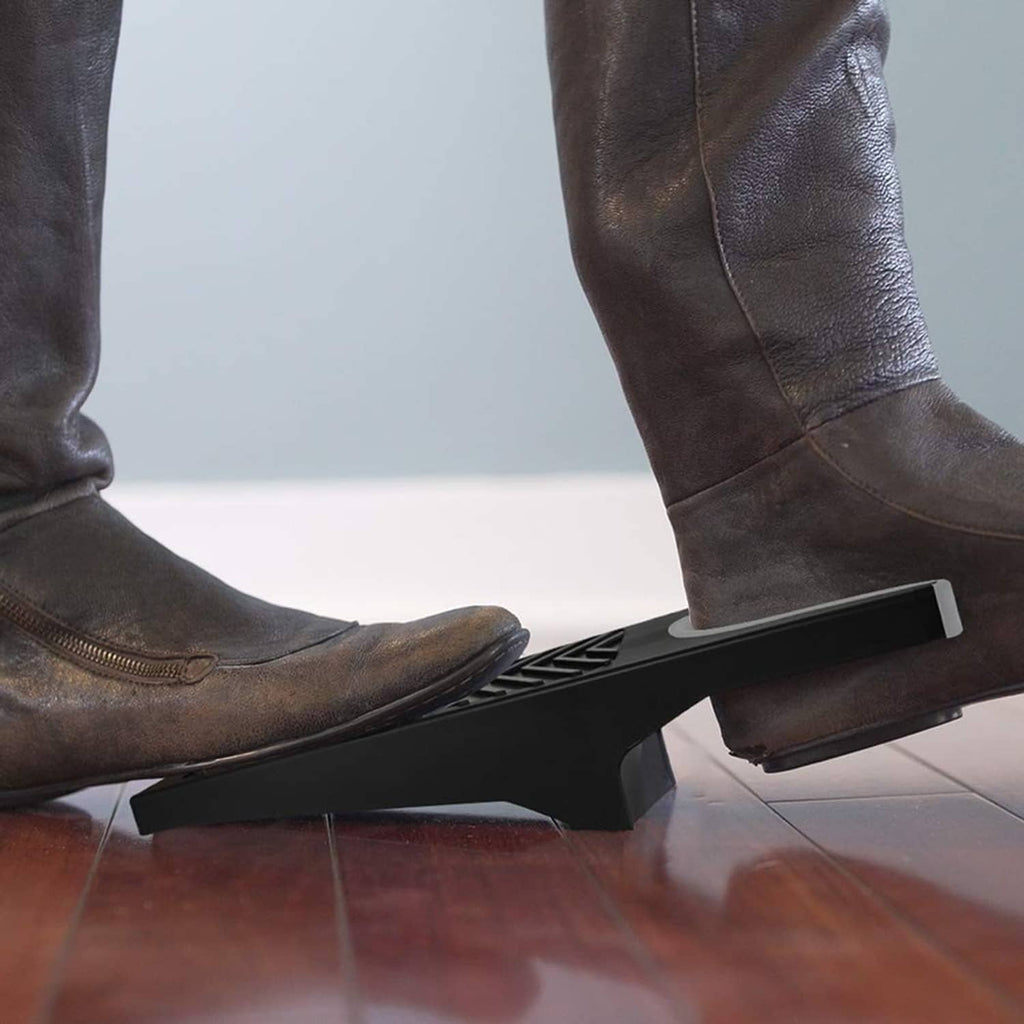 Boot puller tool in use under a leather boot at the floor edge