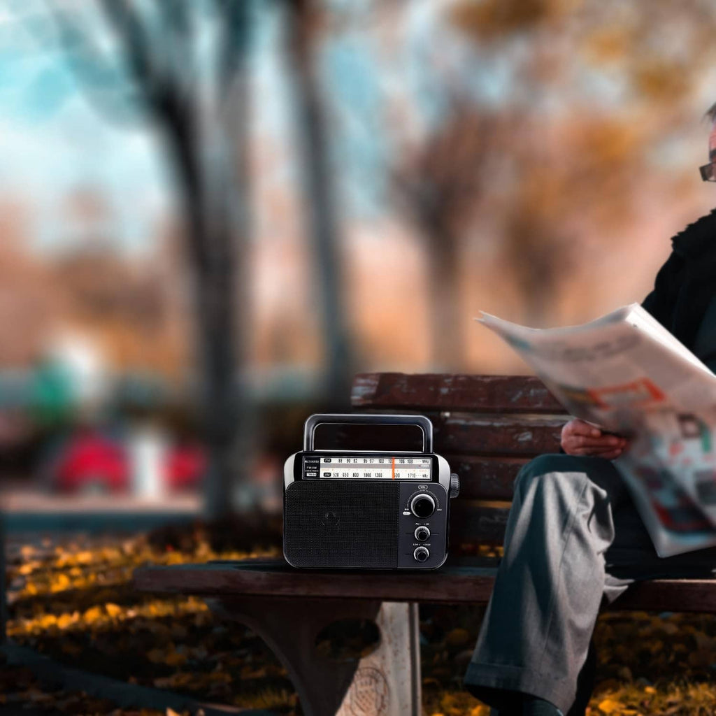 Portable AM/FM radio on a table as a person reads nearby