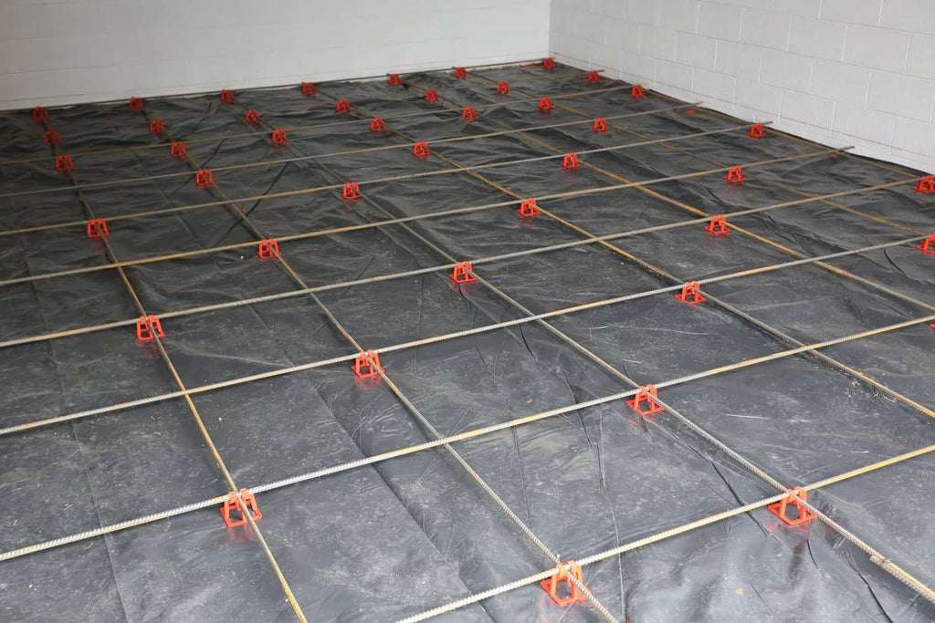 Red plastic rebar chairs securing a rebar grid on a flat surface