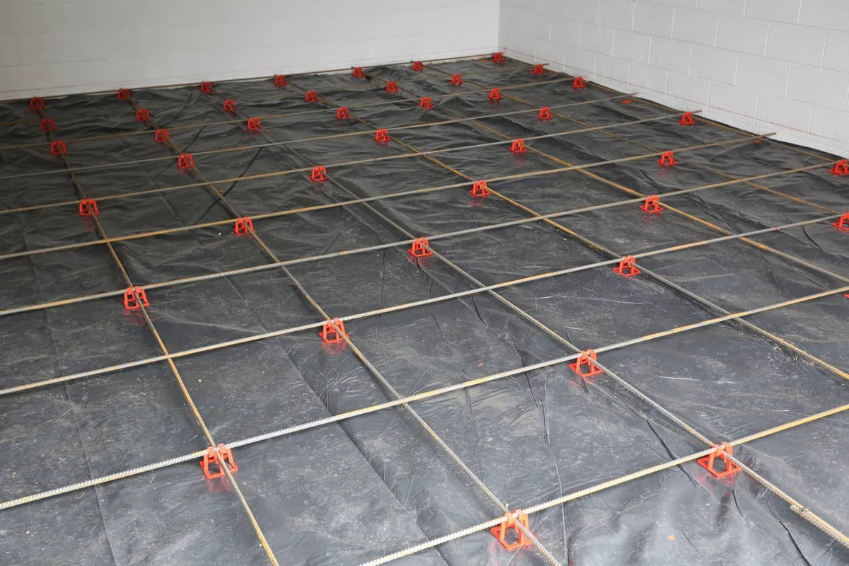 Red plastic rebar chairs securing a rebar grid on a flat surface