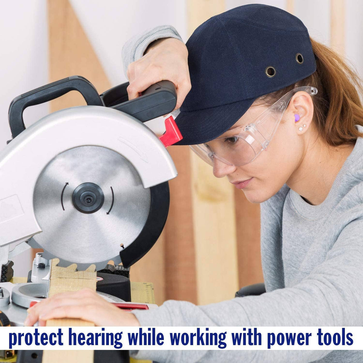 Purple soft foam earplug worn on ear while using power tools, safety glasses visible
