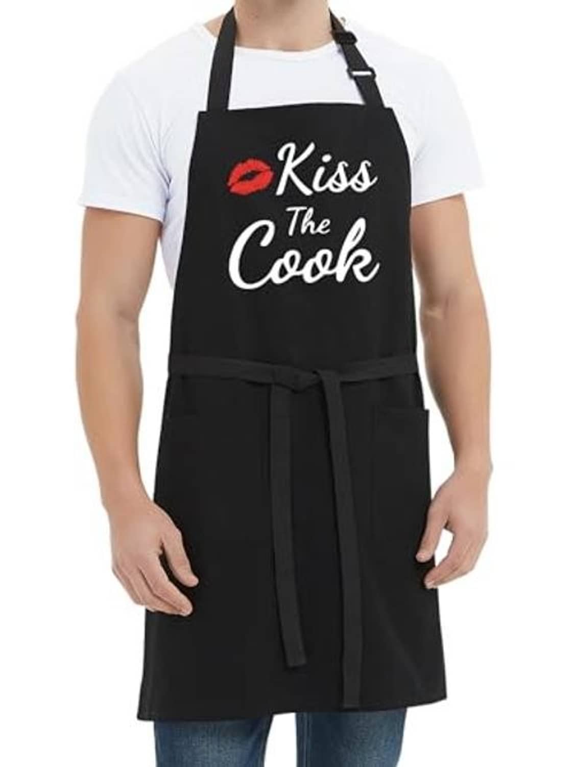 Black apron with tie waist and “Kiss the Cook” logo, worn over blue jeans