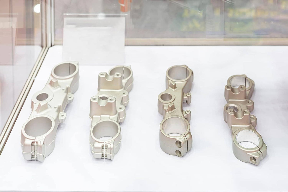 Blast-finished metal brackets and clamps arranged on a white surface