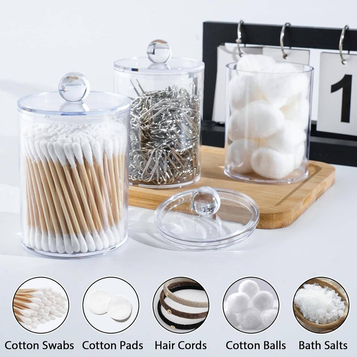 Lidded clear jars holding cotton swabs, cotton pads, and cotton balls for bathroom storage
