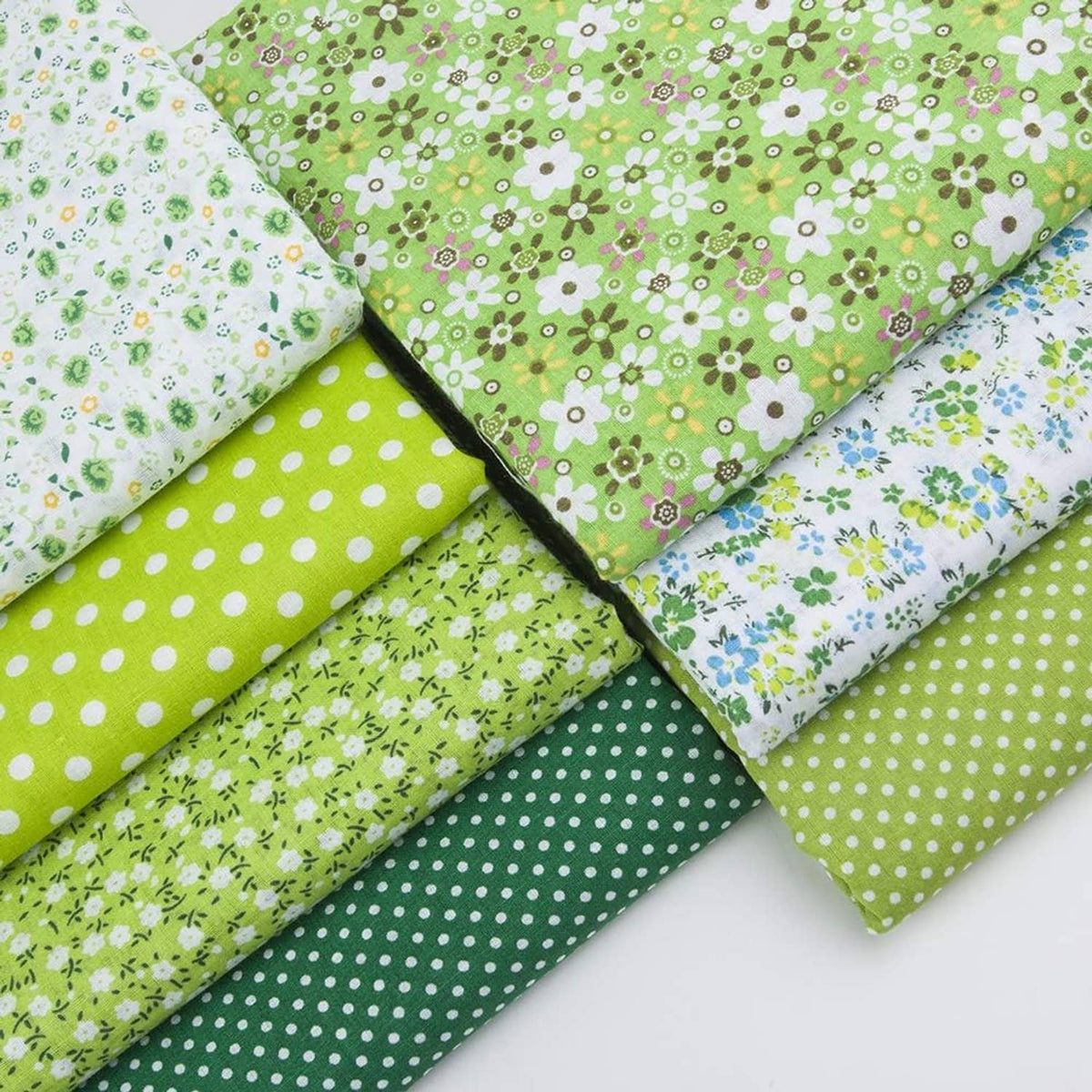 Stack of cotton patchwork fabric squares in green polka dots and floral prints