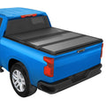Hard tri-fold tonneau cover with black panels closed on a blue pickup bed