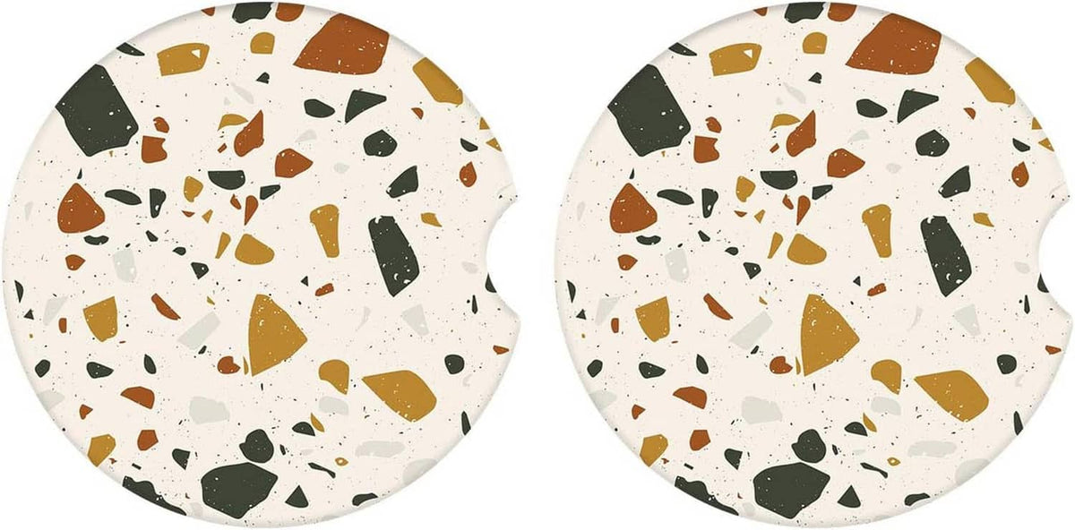 Two round speckled ceramic coasters with brown, green, and white terrazzo pattern