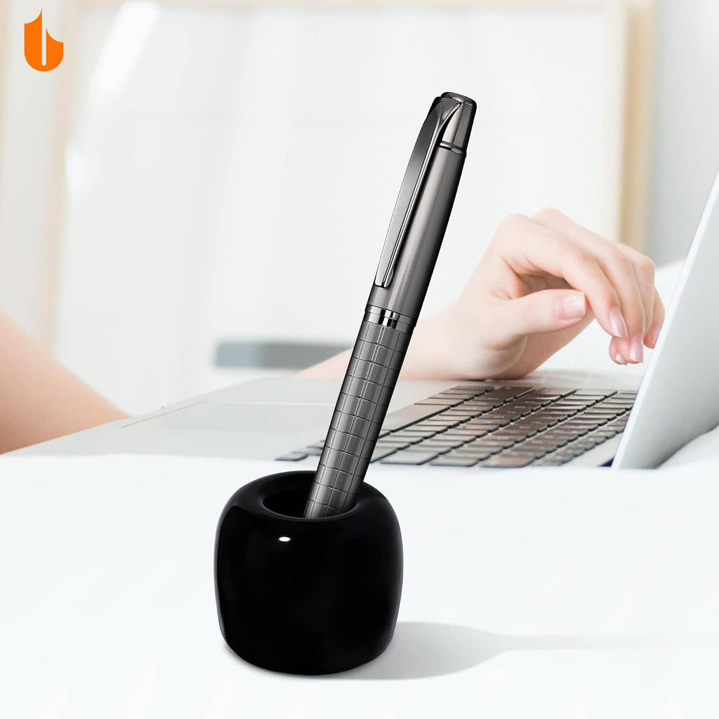 Black ceramic toothbrush holder holding an upright toothbrush next to a computer keyboard.