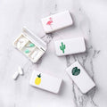 Set of four small white pill organizers with individual compartments and cactus/flamingo icons