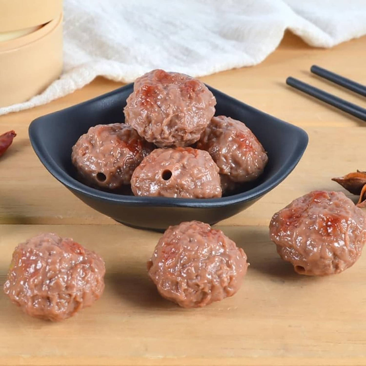 Artificial beef meatballs, brown, in a bowl with several balls scattered around