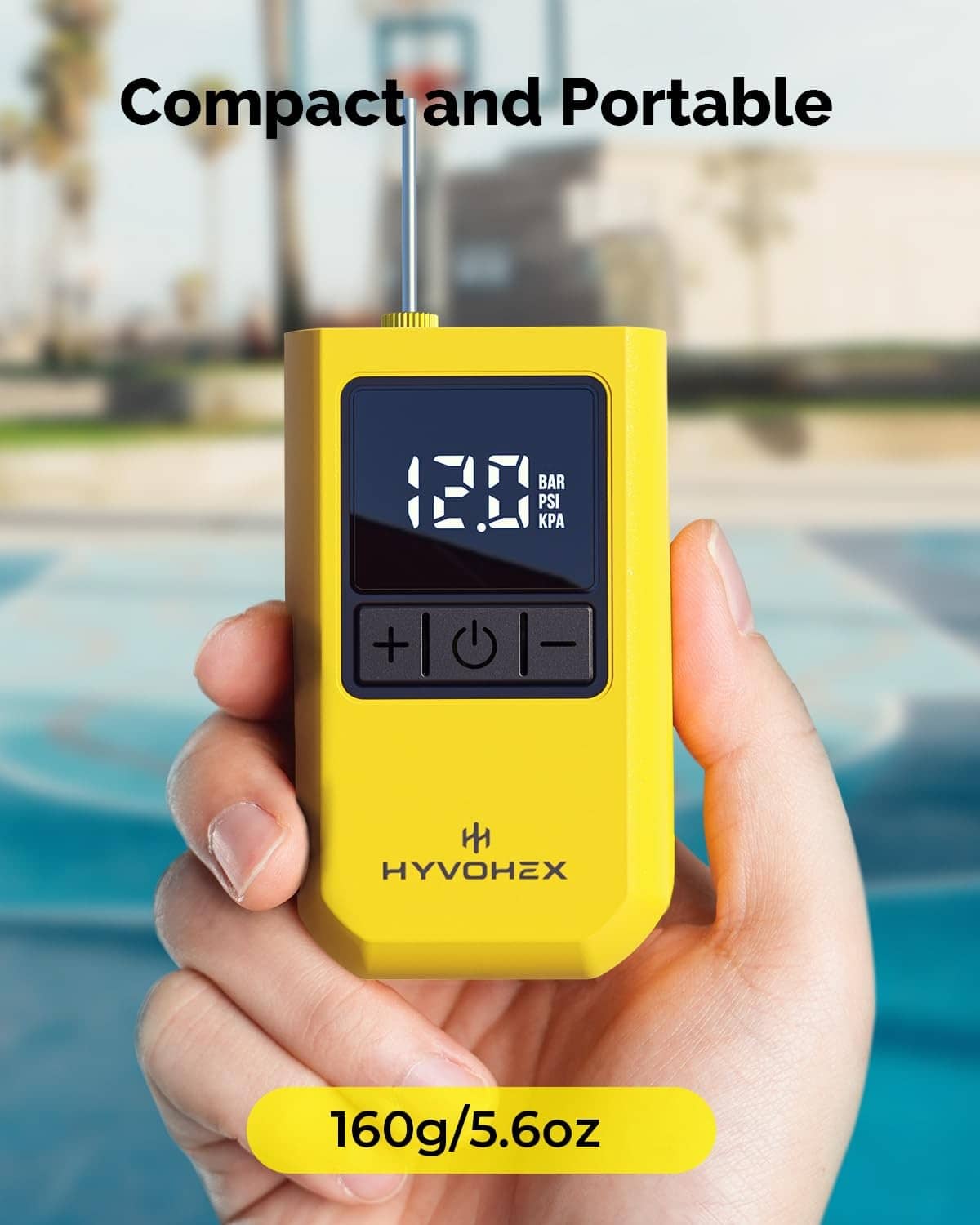 Yellow portable electric ball pump held in hands with digital pressure readout