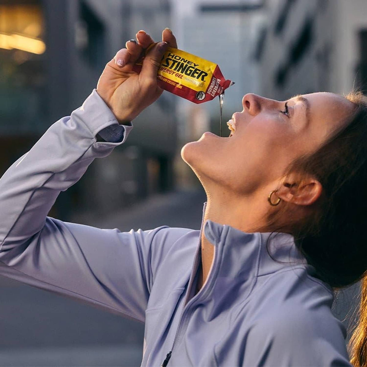 Honey Stinger energy fuel packet held before a sip from a drink