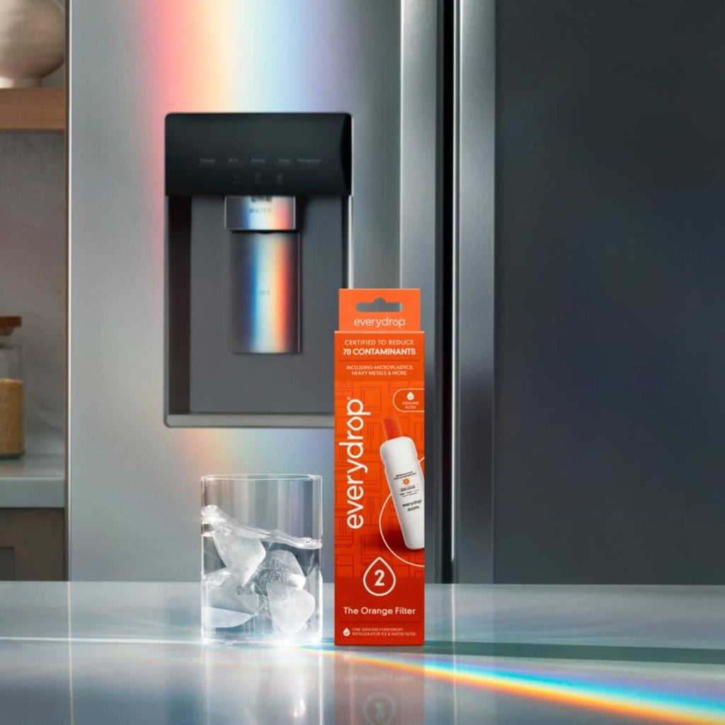 Refrigerator water filter box and cartridge with orange top in front of dispenser