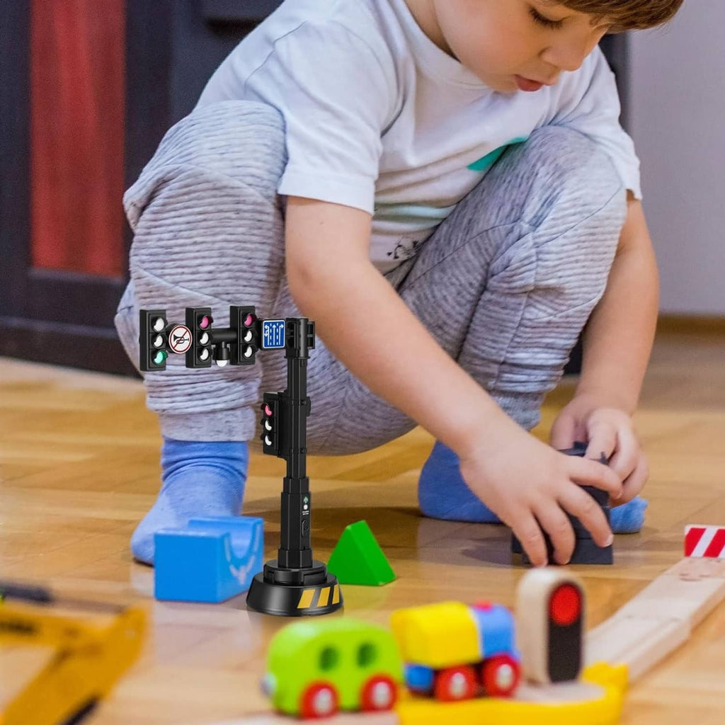 Child playing with black interactive traffic light toy on tabletop with toy vehicles