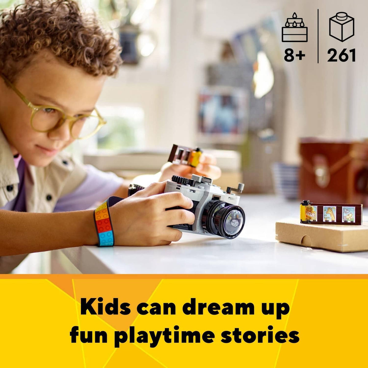 Child holding LEGO retro camera toy with small build on table