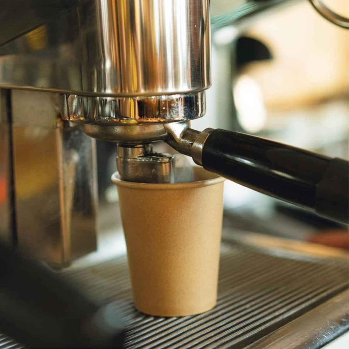 Brown kraft paper cup under a spout, ready for hot drinks