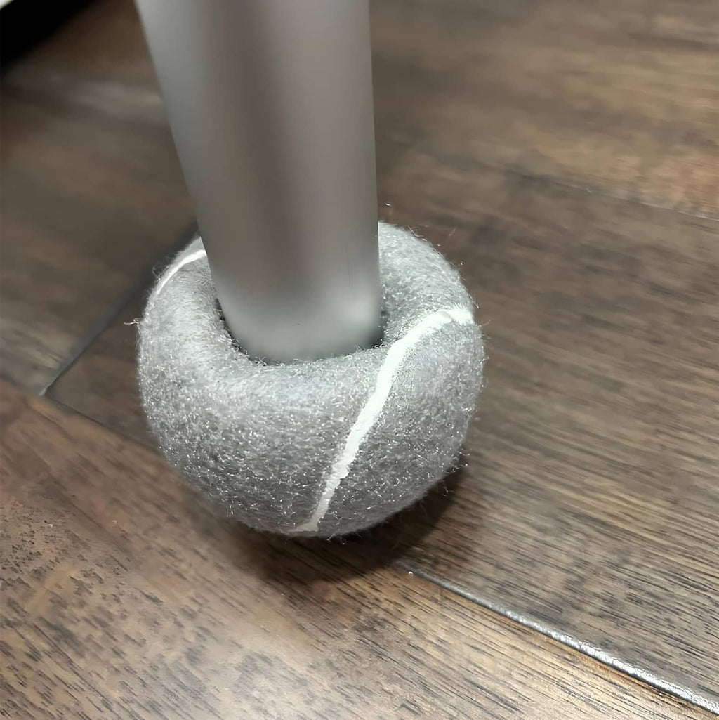 Grey felt ski glide pad with white stripe, under walker leg on wood floor