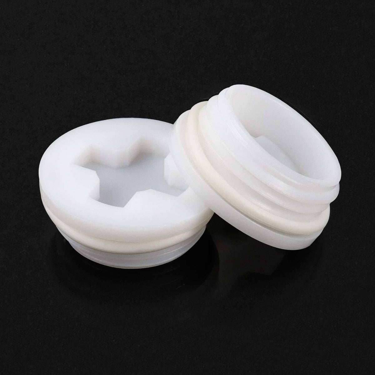 White plastic bung caps pair, showing top opening with star-style drive socket