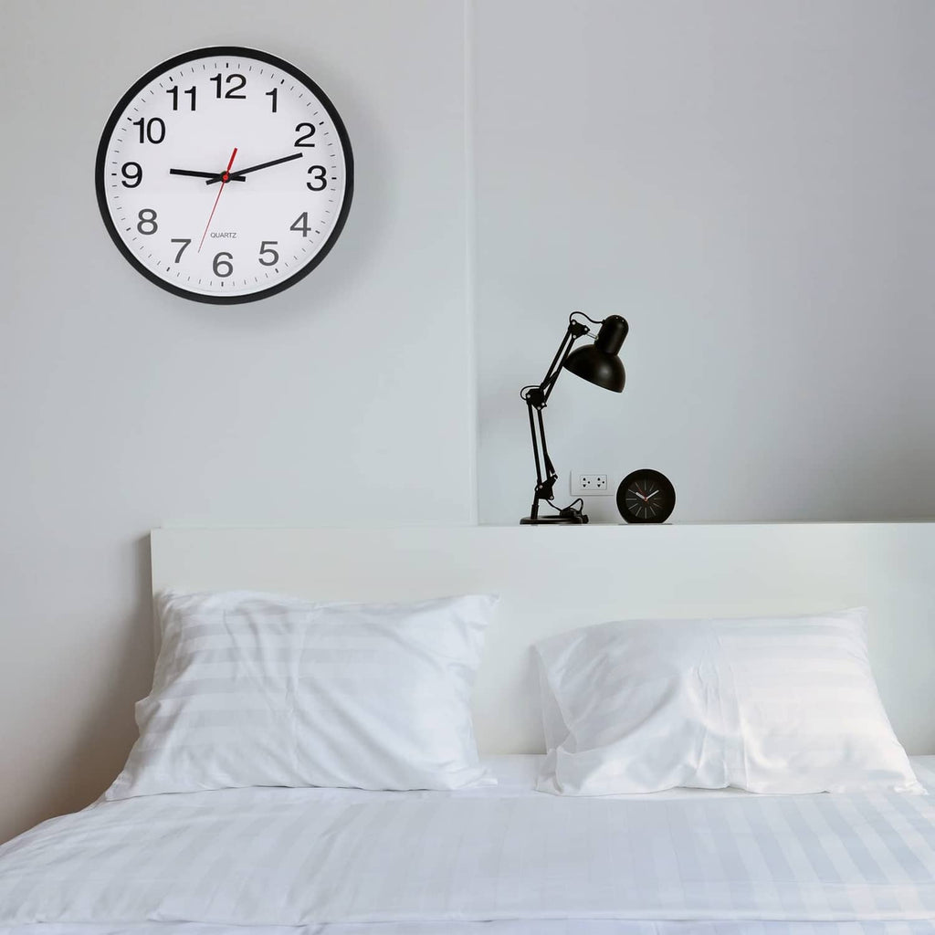 Small black-rim wall clock with white dial, black numerals, and red second hand.