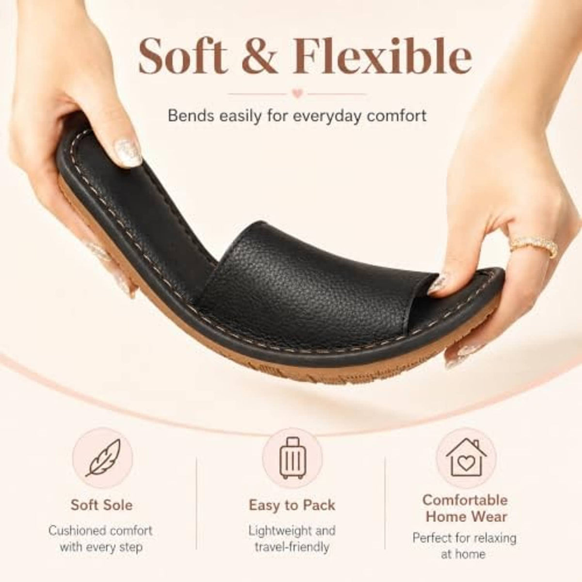 Black open-toe slide sandal slipper held by hand, flat sole with tan edge trim.