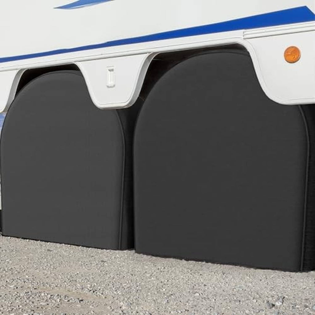 Two black RV tire covers installed under an RV, showing arched front profile