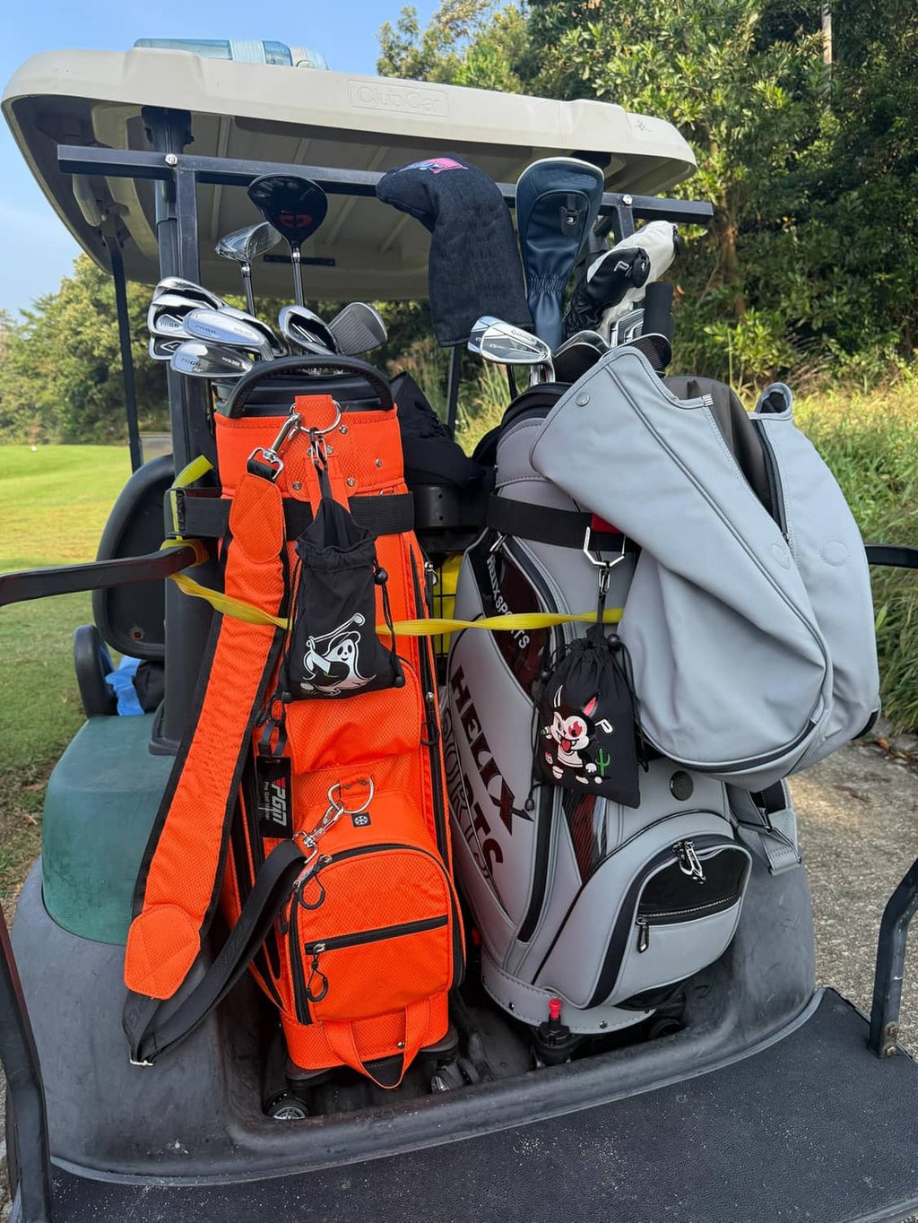 Golf bag accessory: black drawstring pouch with white golfer graphic hanging on the bag.