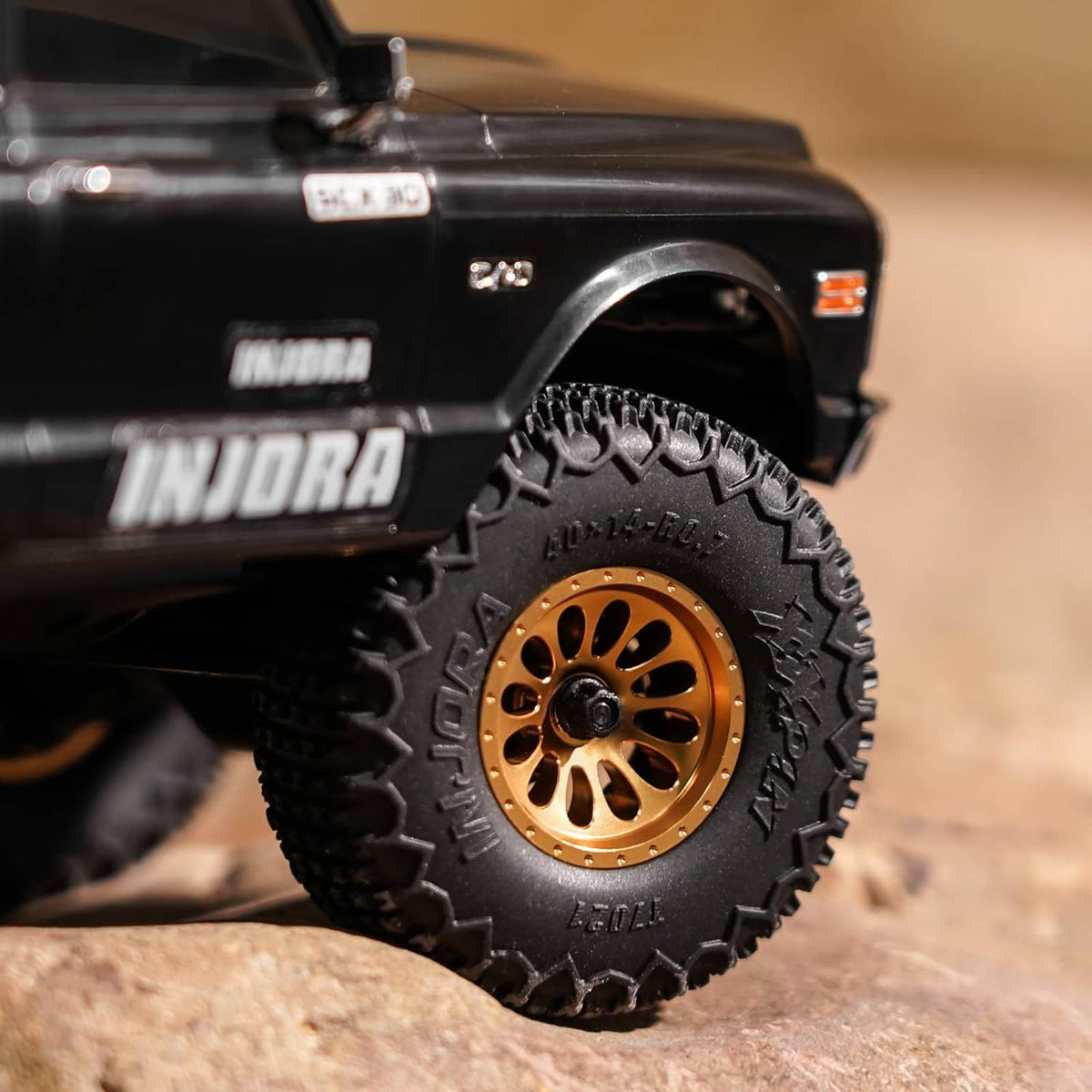 RC truck front wheel with gold beadlock rim and black tire tread