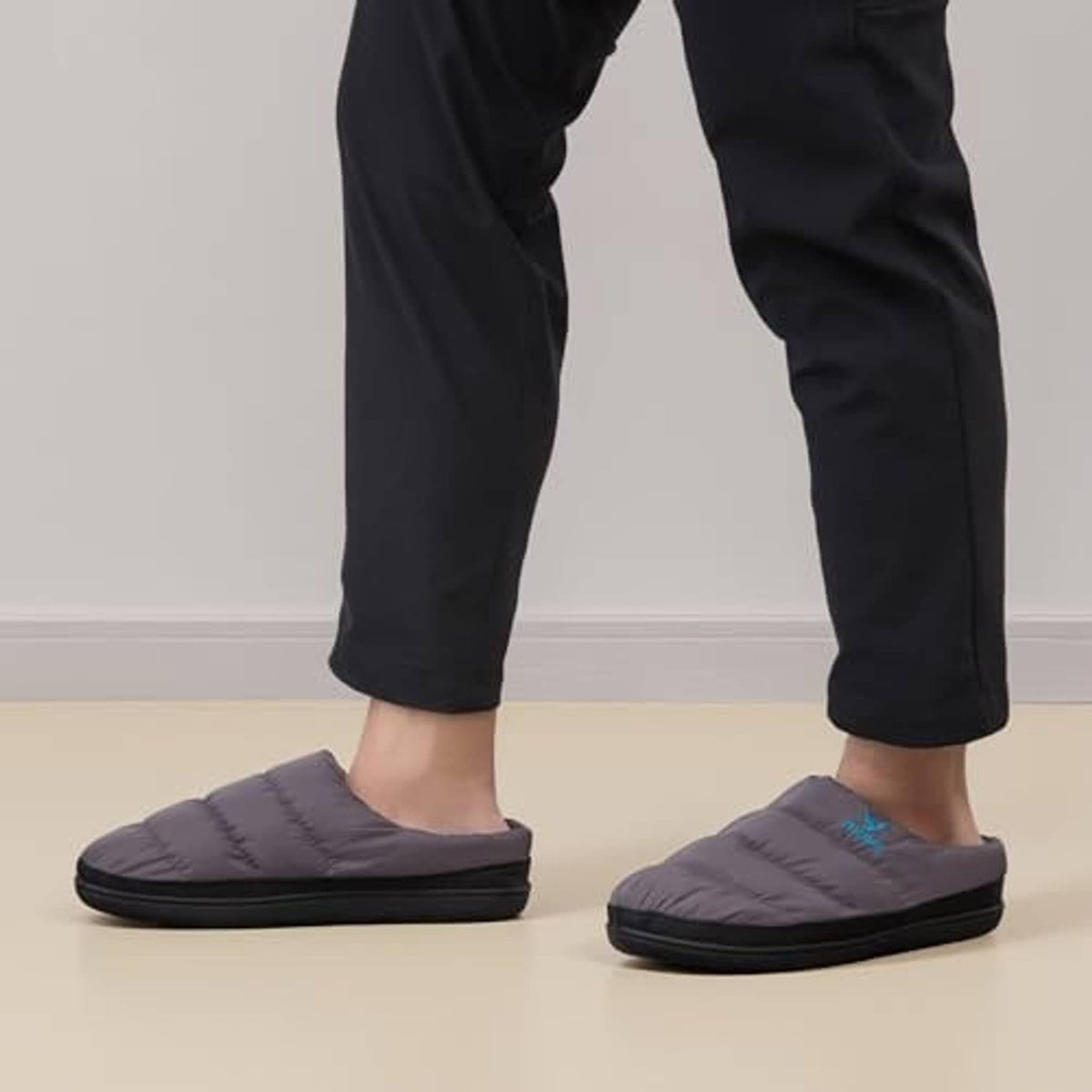 Two-tone slip-on slippers on feet, dark gray upper with bright blue interior