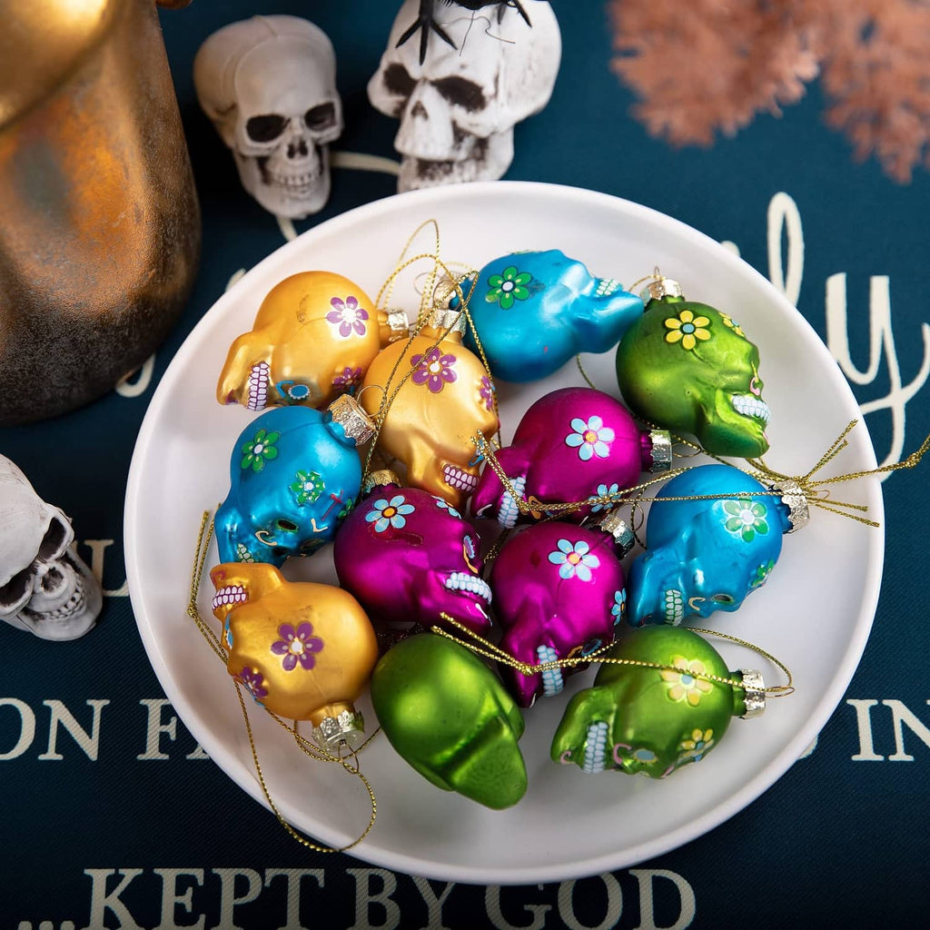 Mixed Day of the Dead glass skull ornaments with hanging loops on a white plate