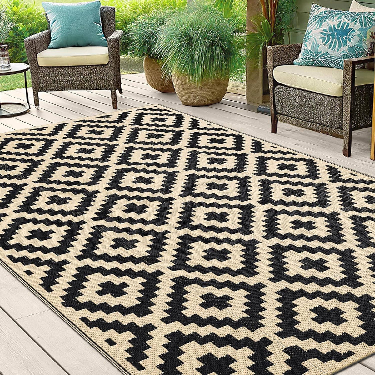 Black and beige geometric outdoor rug with diamond cross pattern, flat woven texture.
