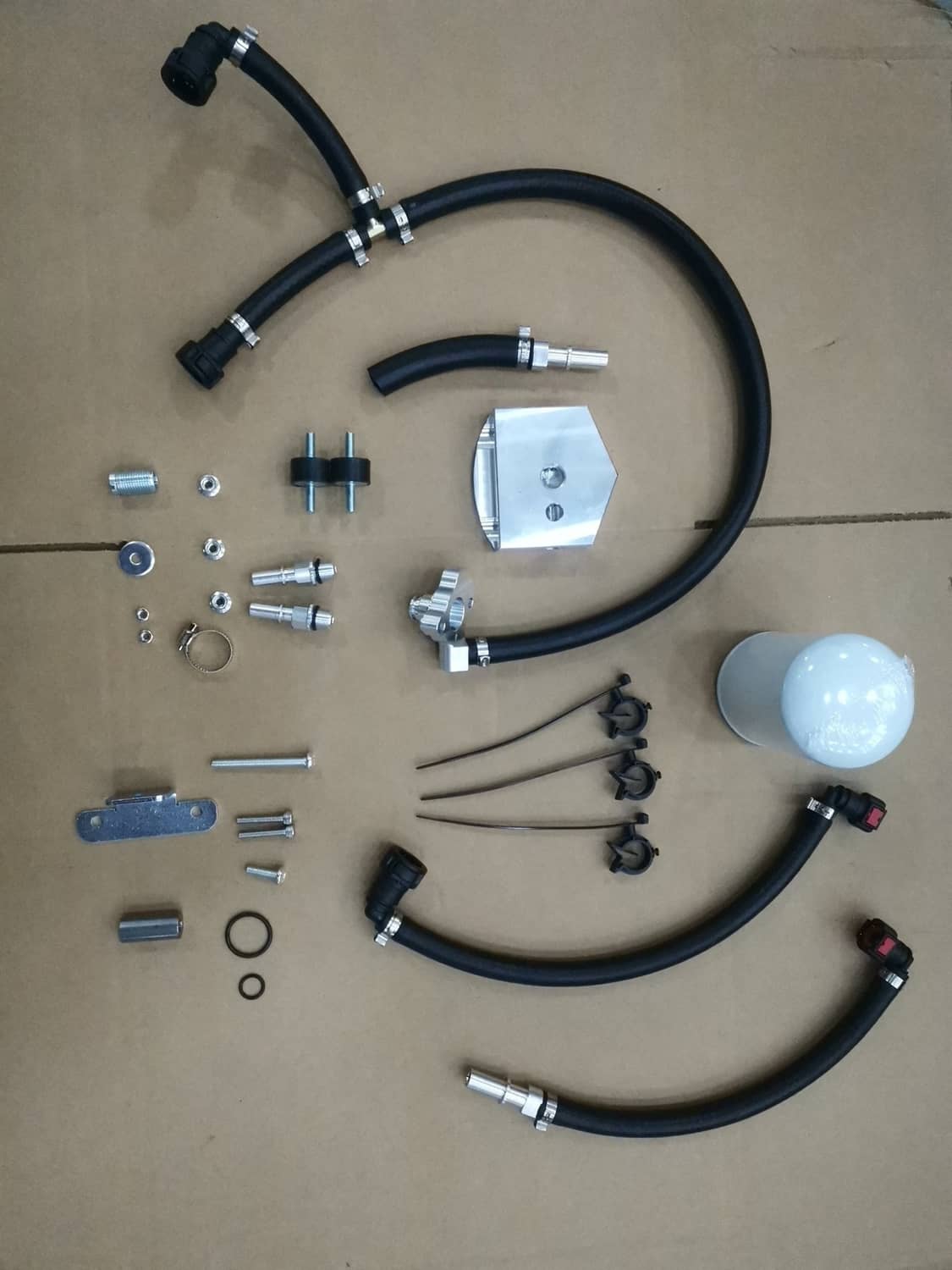 Bypass kit components laid out: black hoses, fittings, metal bracket, and filter canister