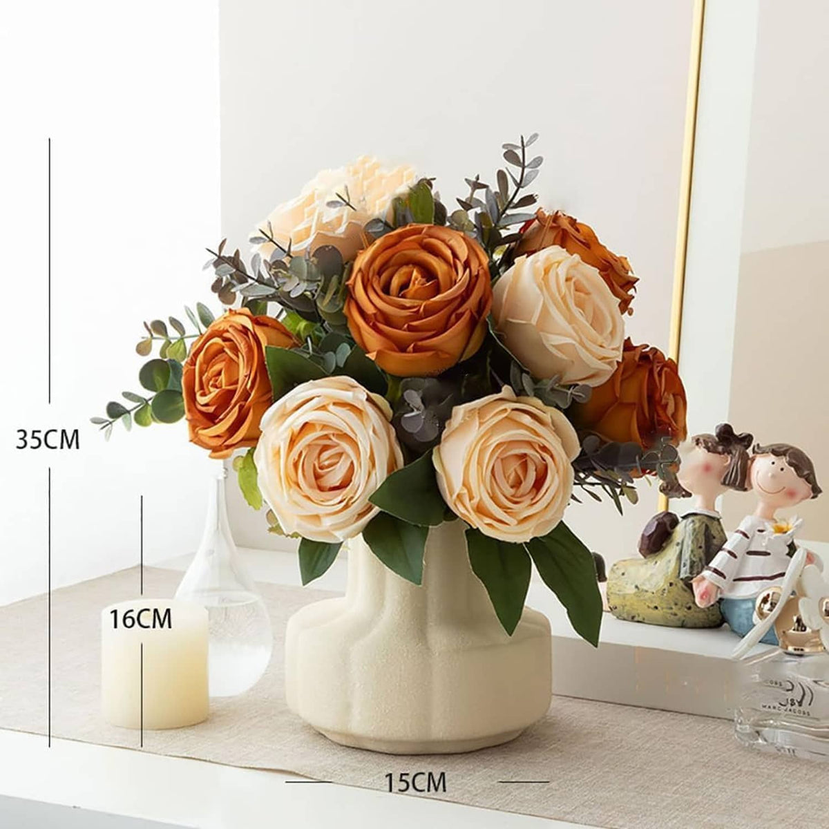 Artificial rose bouquet in cream vase with orange and white roses, eucalyptus sprigs, and figurine