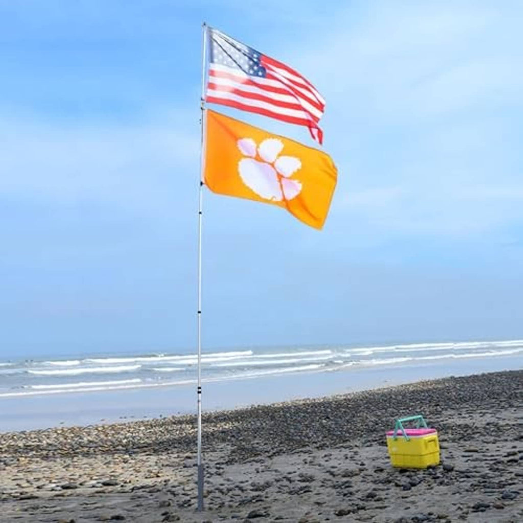 Ground flagpole mount with U.S. and yellow printed flags on a tall pole