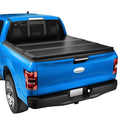 Black tri-fold hard tonneau cover on a blue pickup truck bed