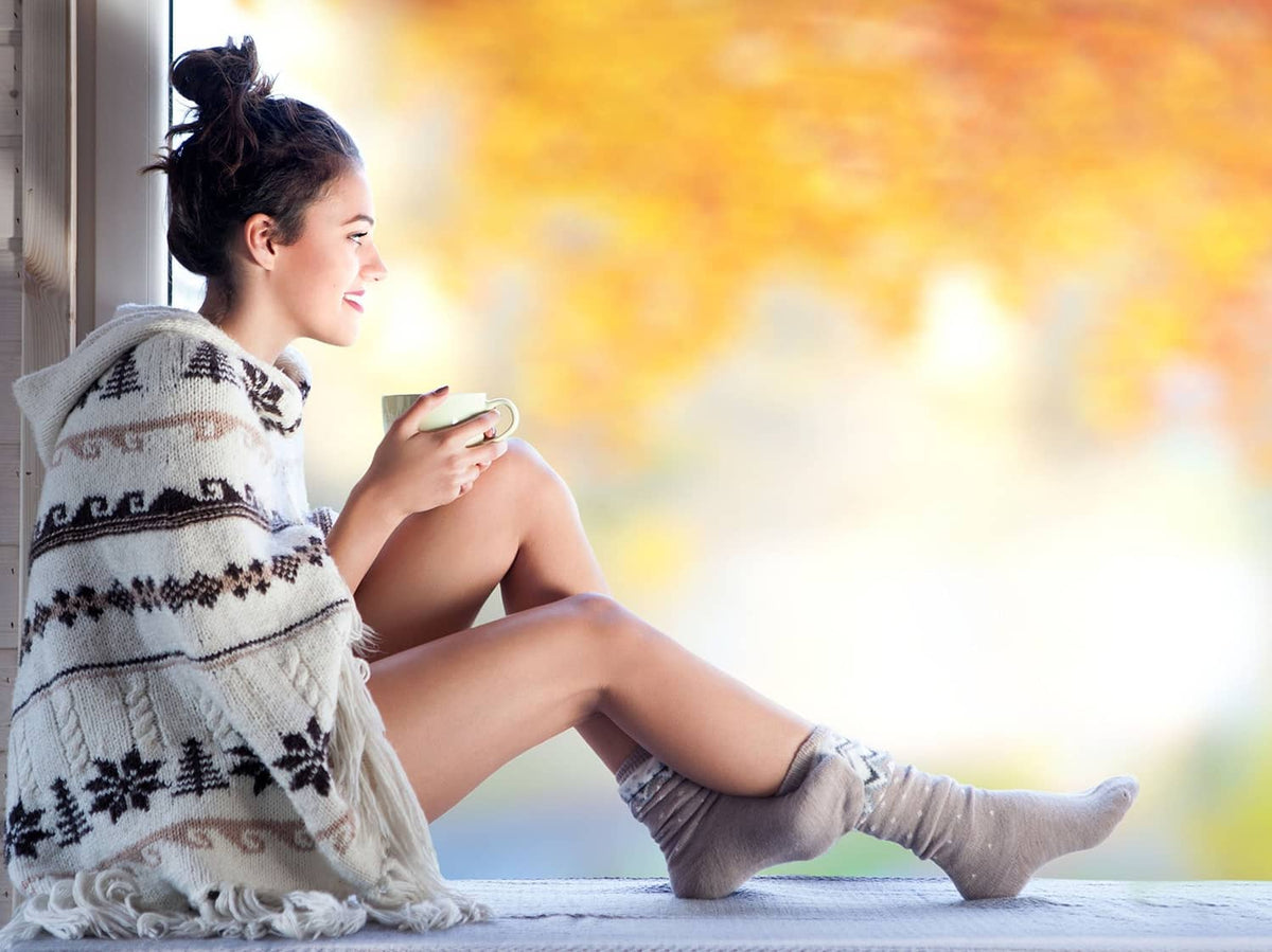 Lemon balm tea cup held by a person lounging with herbal leaves