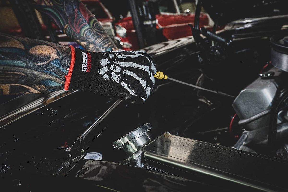 Mechanic glove on hand, black with white bone graphic and red knit cuff