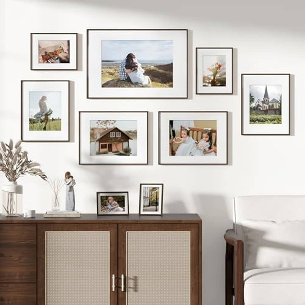 Wall photo display with multiple walnut frames, including 6x8 matted images
