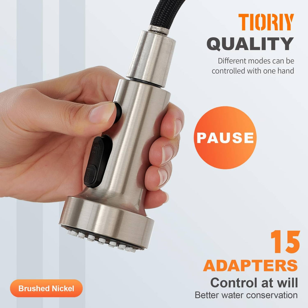 Brushed nickel faucet head with black pause switch, gripped by hand