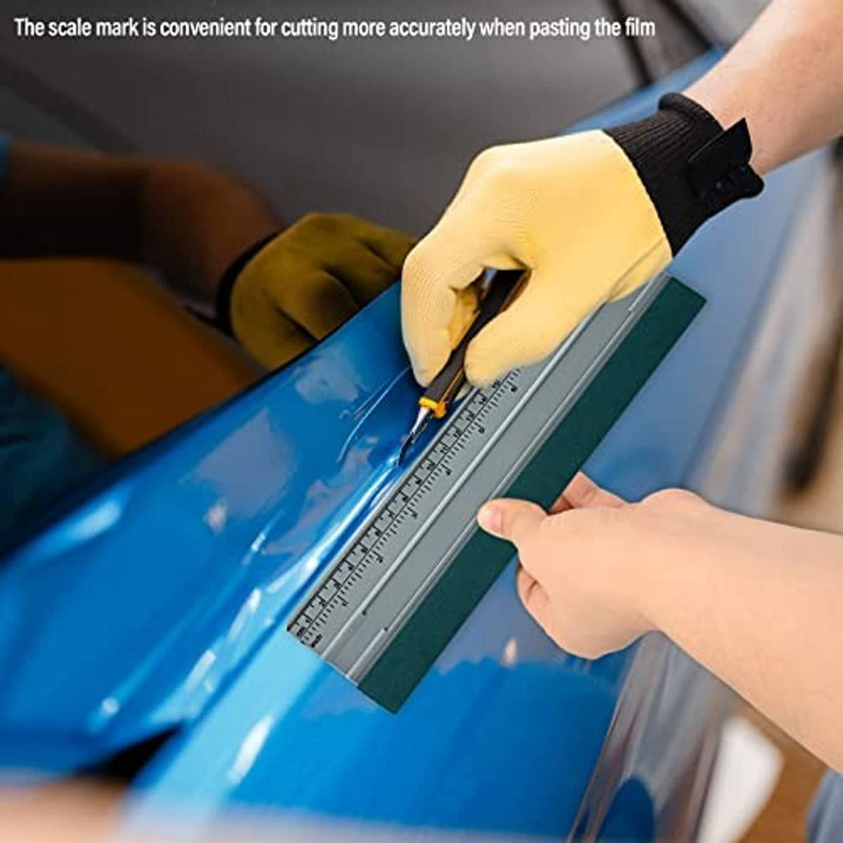 Felt squeegee guiding vinyl film with built-in ruler for accurate placement