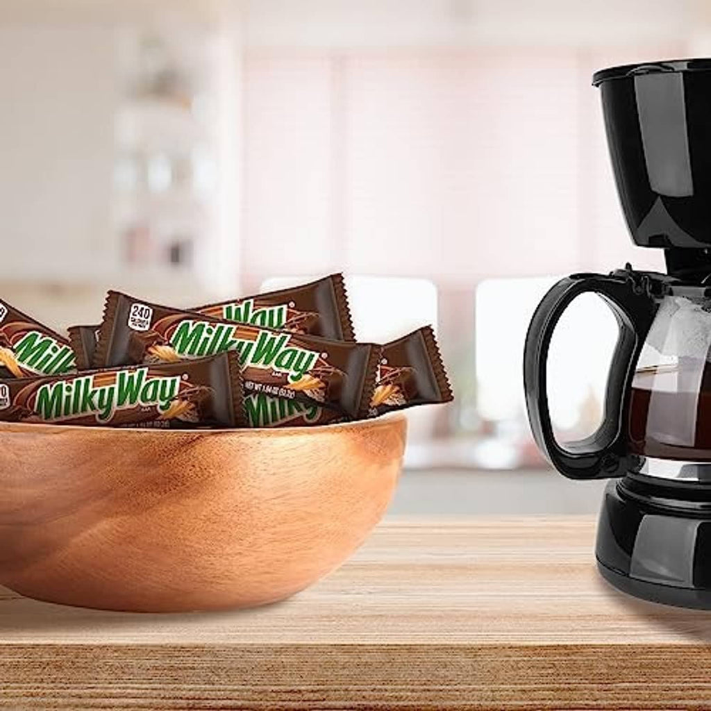 Milky Way milk chocolate bars in wrappers on counter near a coffee maker