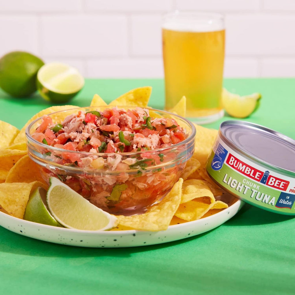 Chunk light tuna in water bowl with tortilla chips, lime, and tuna can