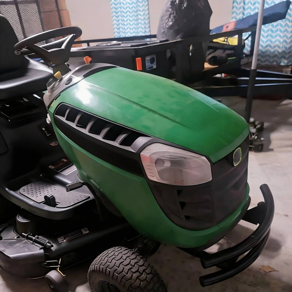 Front view of a green lawn tractor showing the black bumper guard