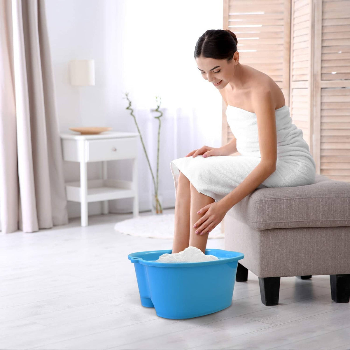 Blue foot bath tub with soaking feet on the floor beside a seated person