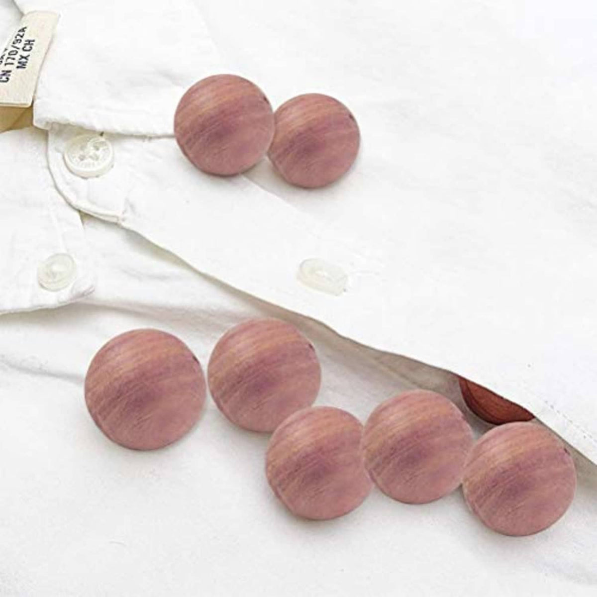Cedar blocks on folded white clothing, round purple-brown wooden discs.