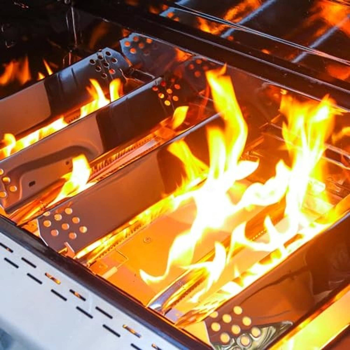 Stainless steel heat shield plates inside grill with flames beneath