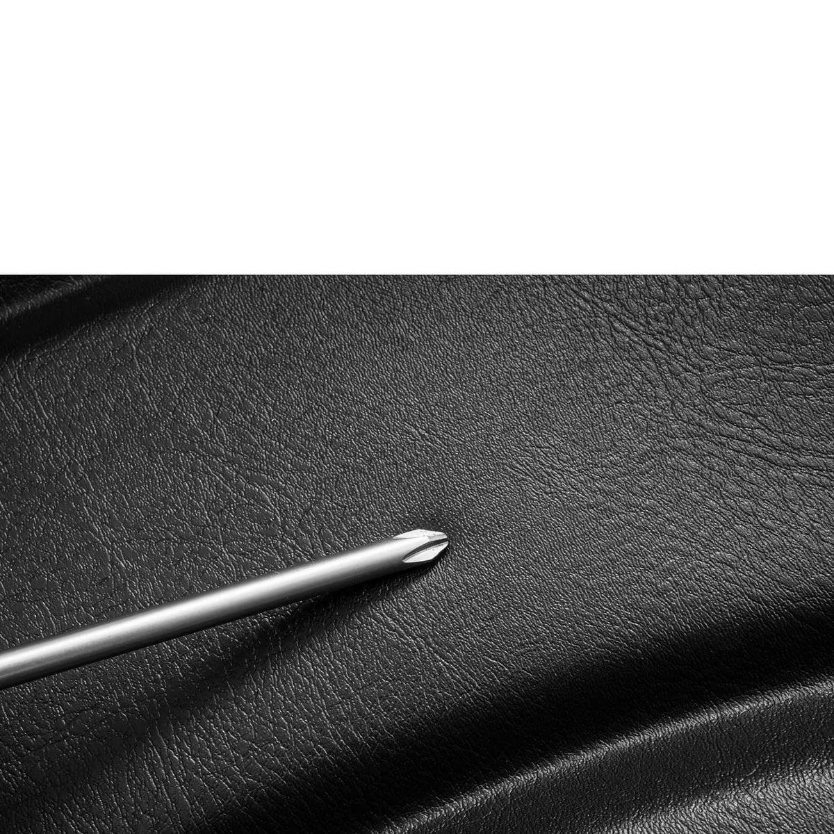Close-up of black vinyl seat texture with metal tool tip