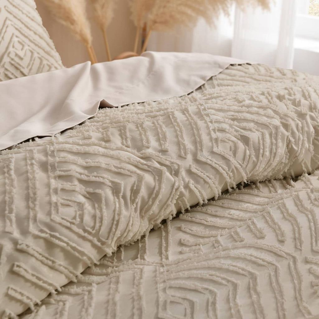 Close-up of light beige quilted comforter with raised geometric stitching and fringe edges